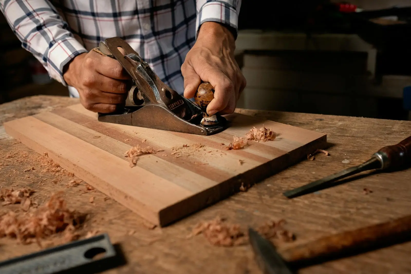 Hands working wood with a hand plane